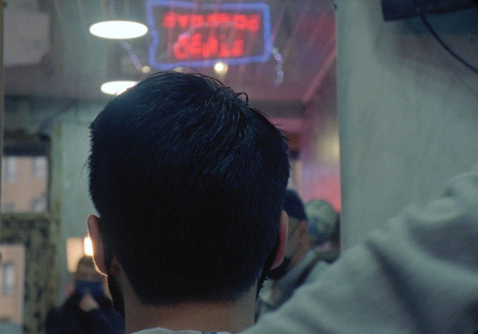 An image of a red neon light sign on a blue square outline, which reads -gents barbers- inverted, as it was photographed from the inside of the shop (the sign points outwards)